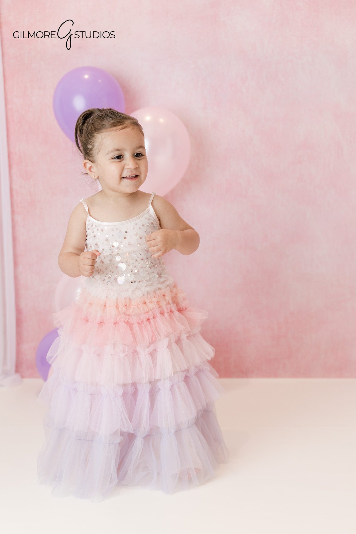 Pink and purple cake smash setup with toddler and pastel balloons
Toddler eating frosting during Queen Creek AZ birthday session