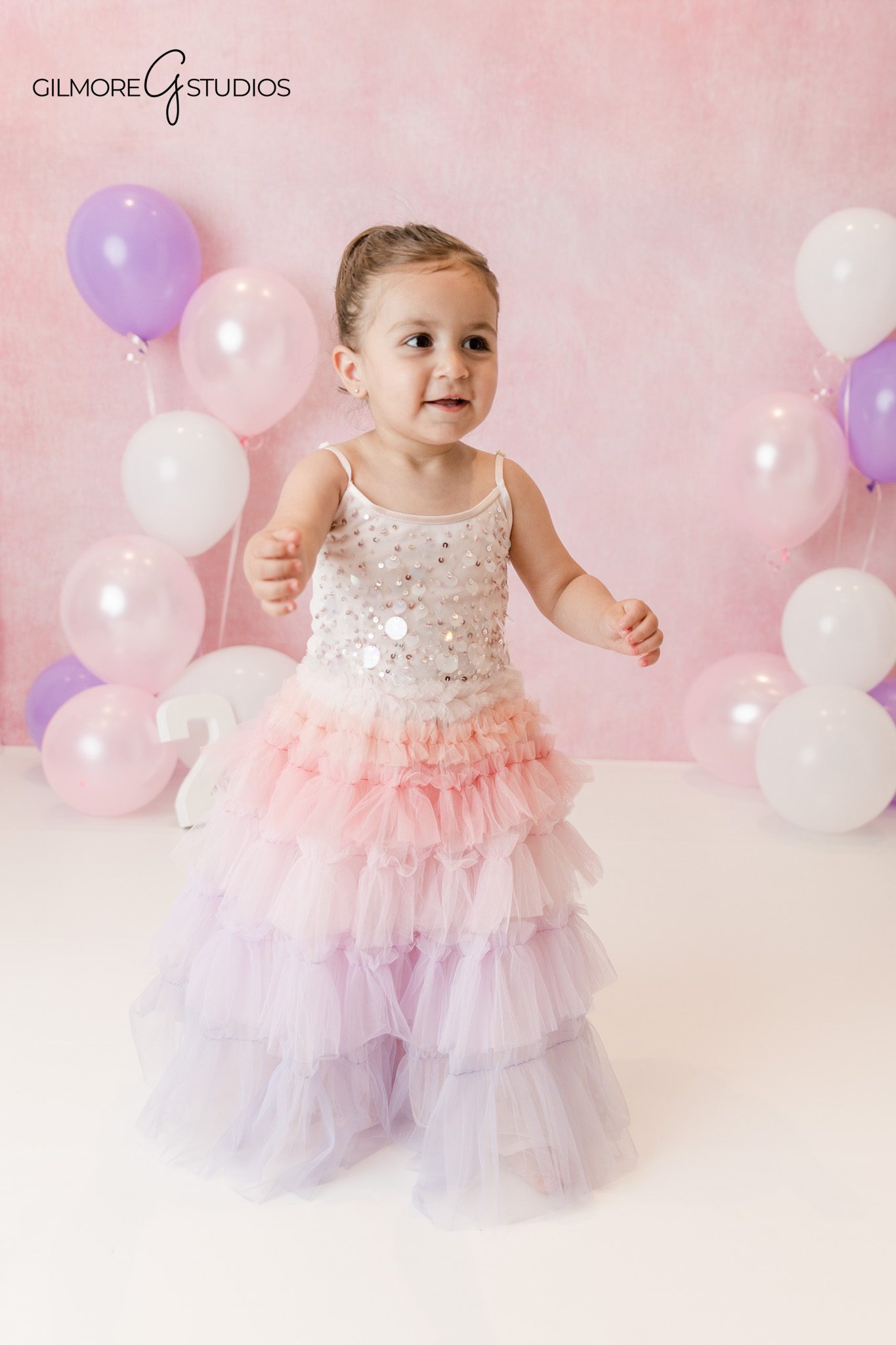 Queen Creek cake smash portrait with balloons and pastel birthday backdrop
Toddler birthday photos with pink and purple balloons at Gilmore Studios