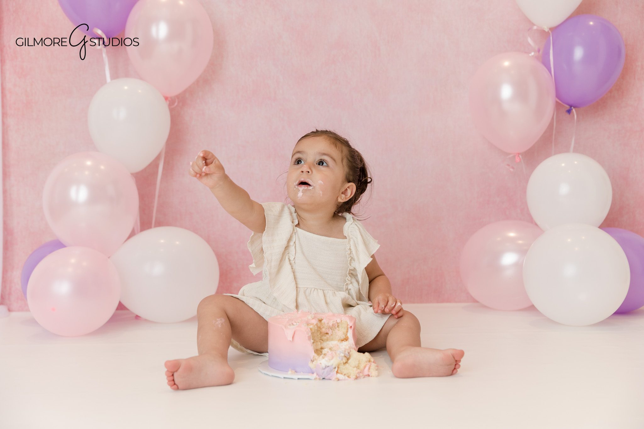 Toddler sitting with pink and purple balloons for second birthday portraits
Pink balloon birthday session for toddler at Queen Creek portrait studio
