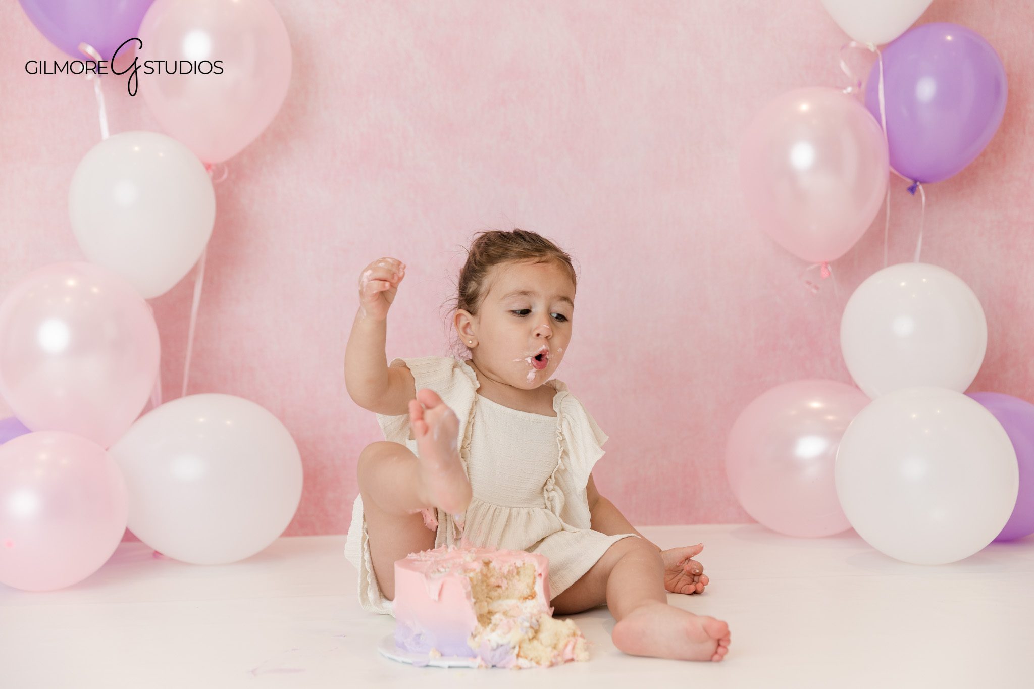 Cake smash photographer in Queen Creek AZ with pastel birthday setup
Toddler birthday portrait with pink backdrop and purple balloons