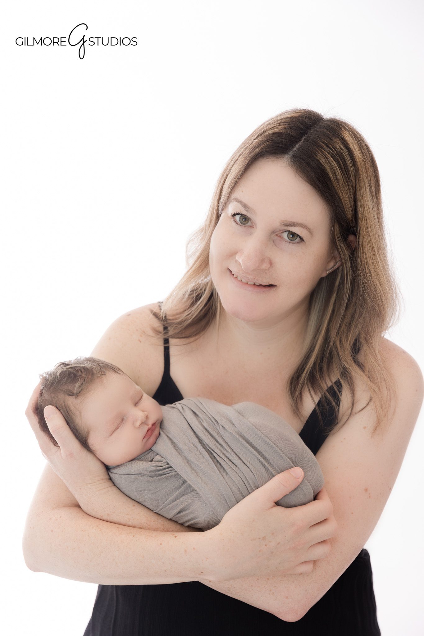 Queen Creek newborn session including sibling portraits
Big sister sitting beside wrapped newborn baby on white blanket