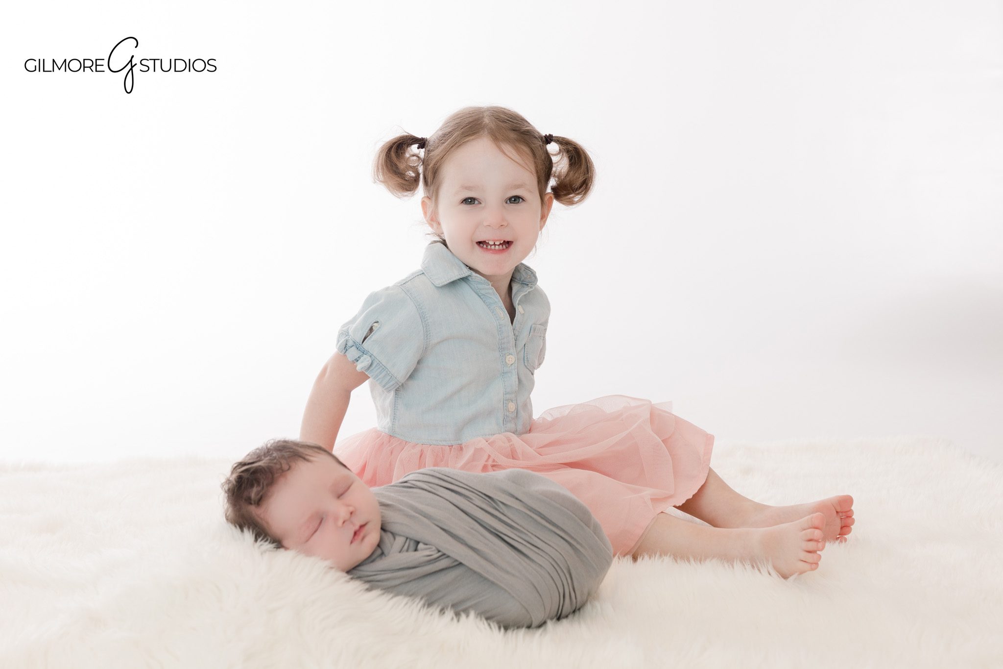 Queen Creek newborn photography with soft sibling connection
Baby wrapped in gray beside big sister in pink skirt