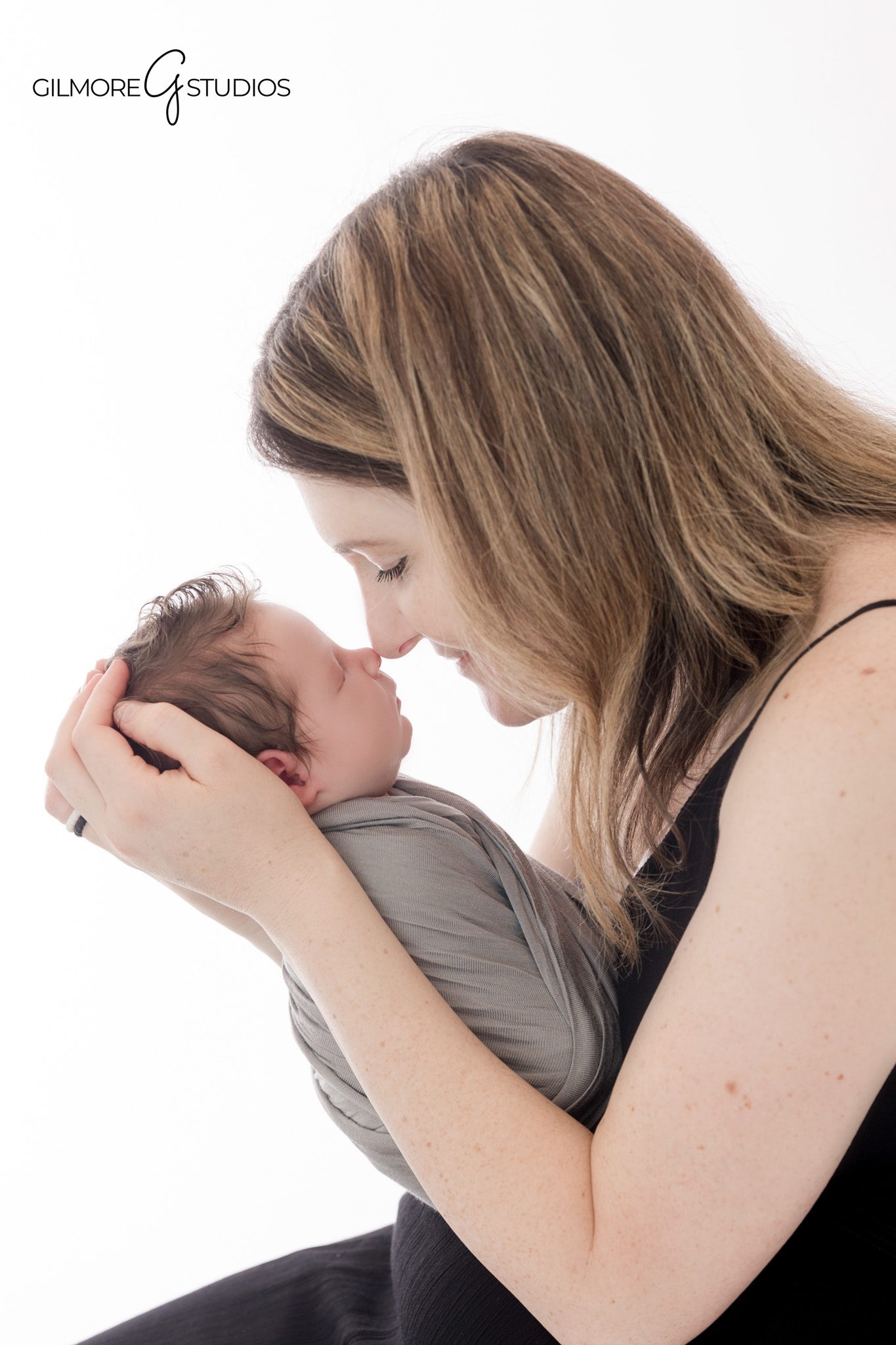 Toddler sibling smiling beside newborn baby in studio
Newborn photography with big sister at Gilmore Studios