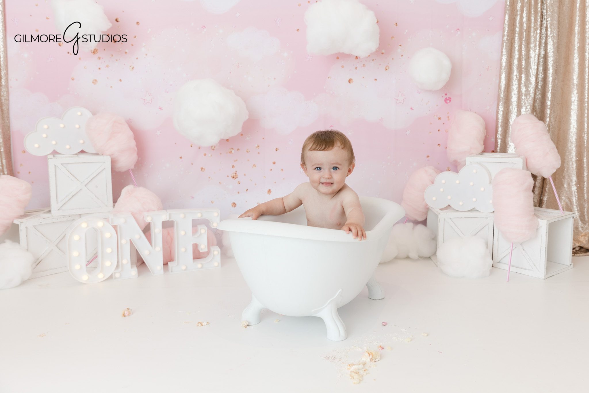 Baby girl in pink tulle dress with first birthday crown
Cotton candy clouds cake smash with ONE marquee letters