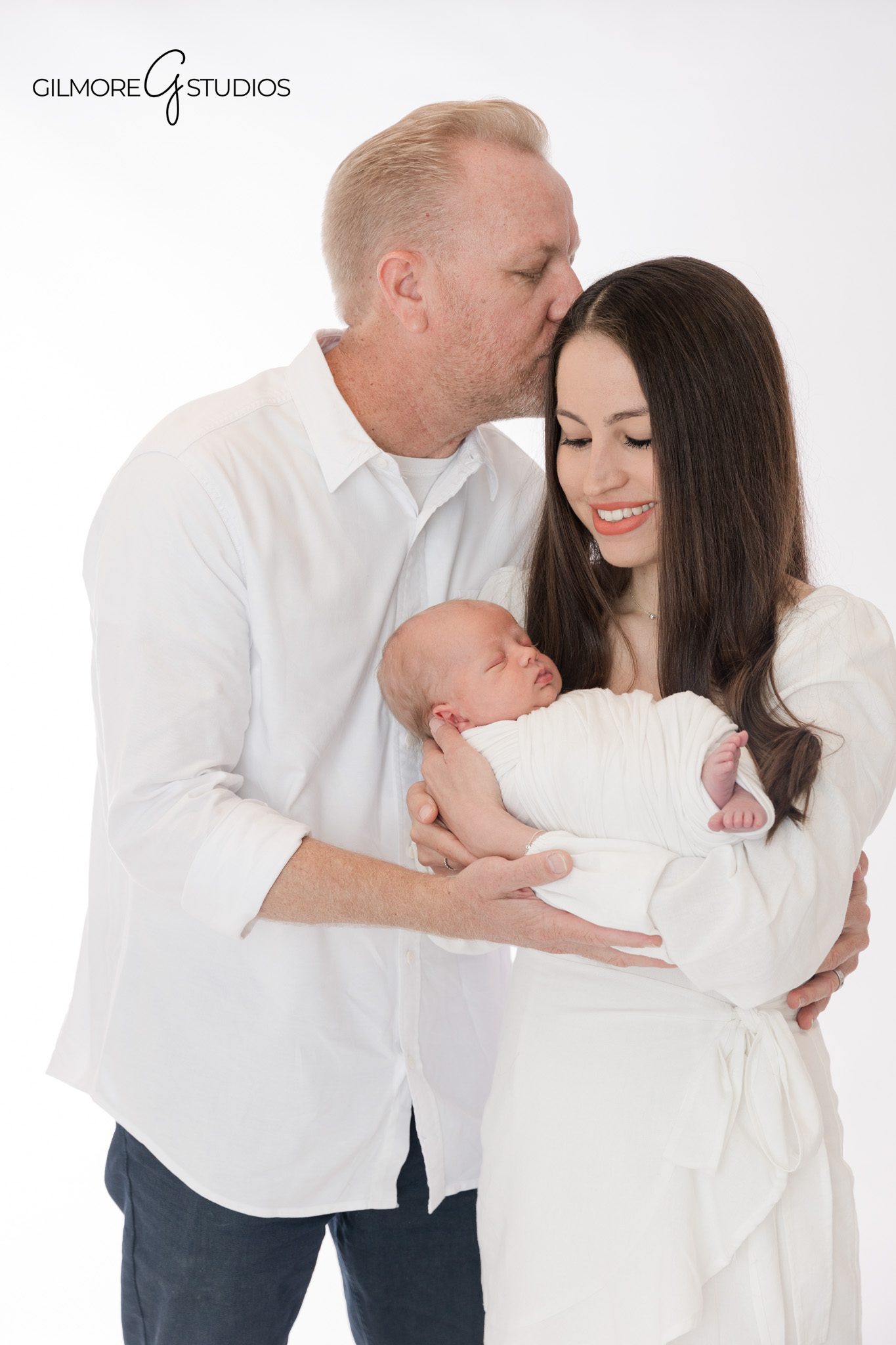 Parents smiling with newborn baby during studio portrait session
Newborn family photos in Newport Beach with soft white styling