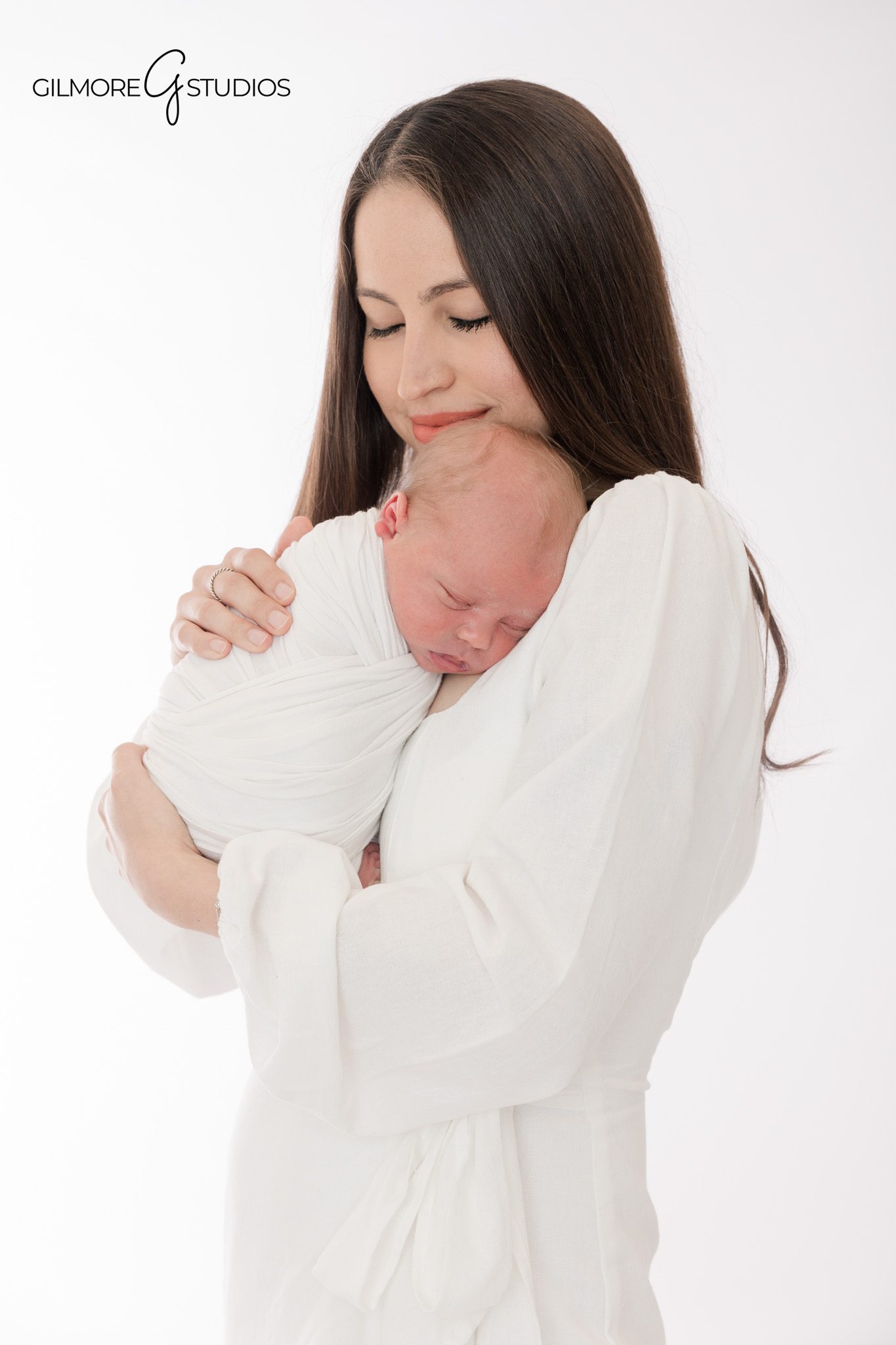 Mom holding newborn baby close in white studio newborn photos
Newborn baby sleeping on mother’s shoulder in Newport Beach studio