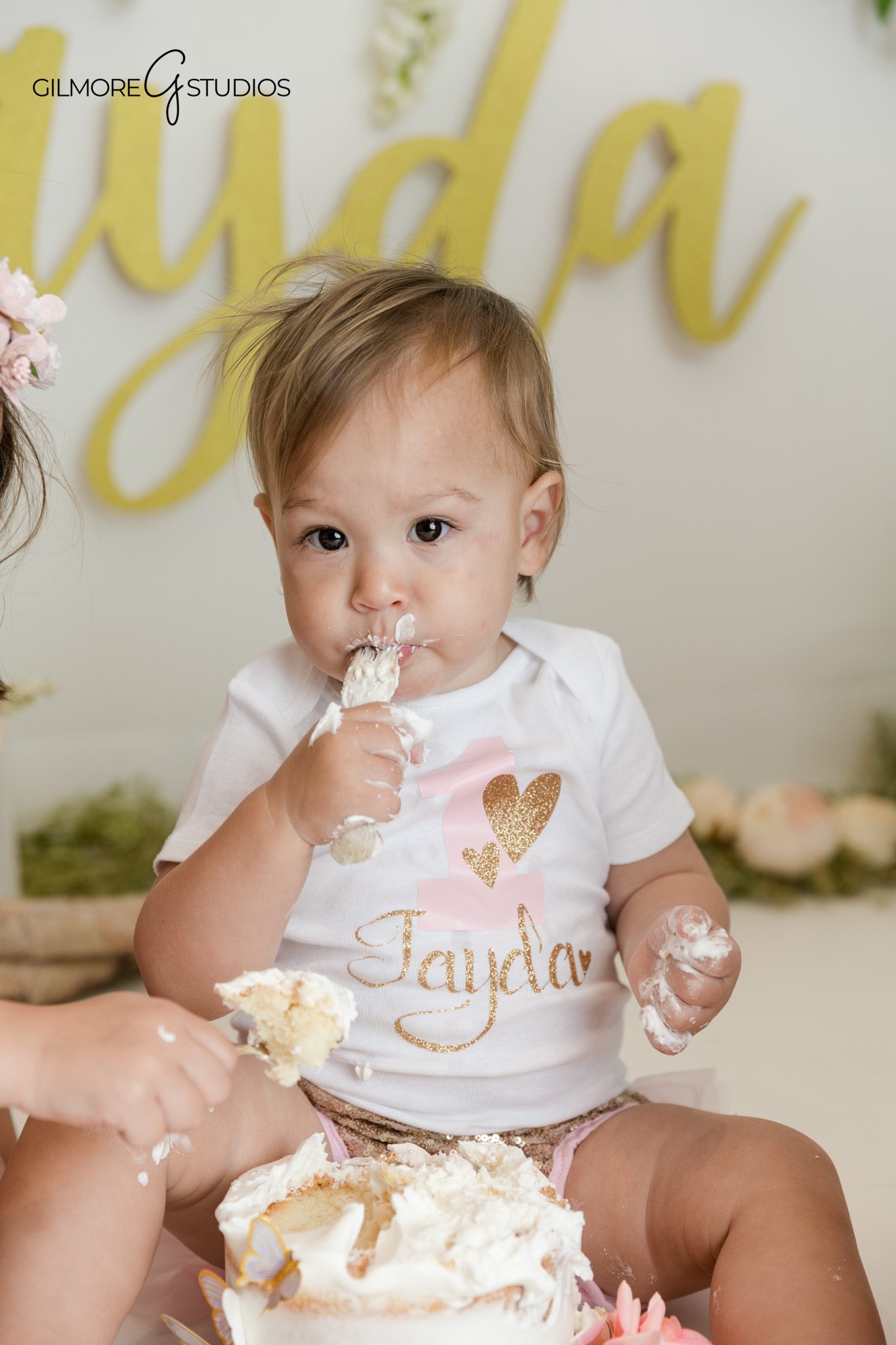 Queen Creek first birthday photography with floral studio backdrop
Baby girl sitting by first birthday cake in boho floral setup