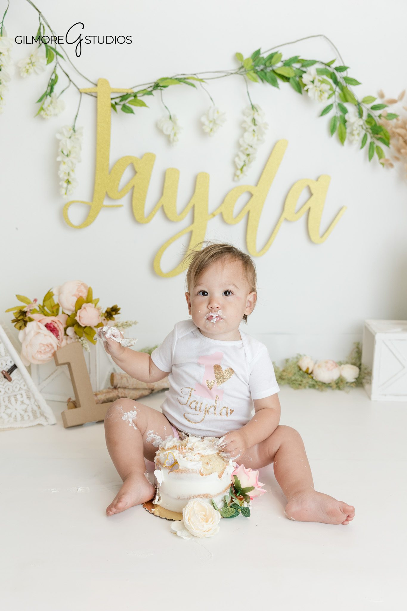 Baby girl first birthday portrait with flowers and soft neutral decor
Boho floral cake smash setup with blush flowers and greenery