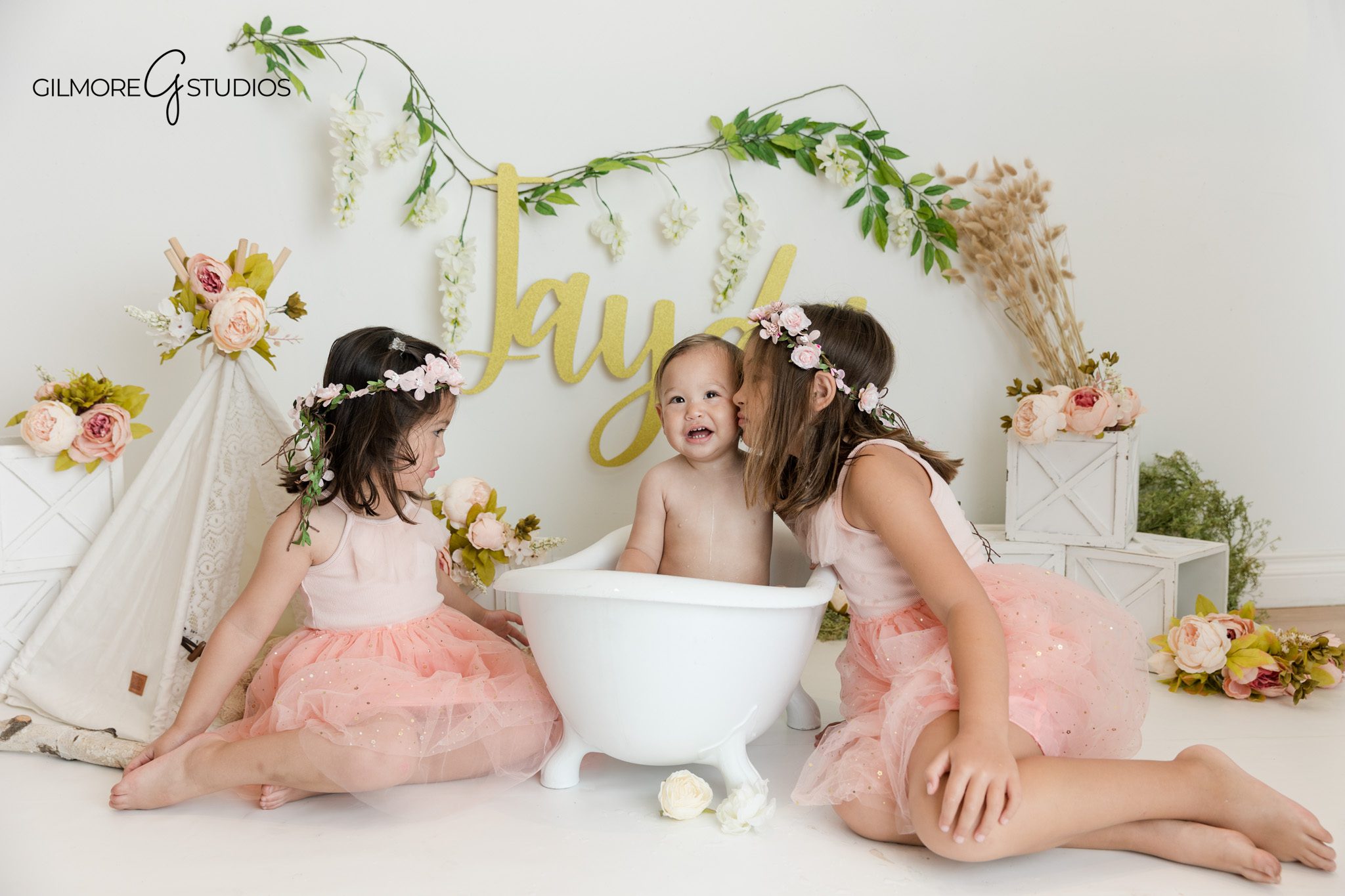 Boho floral one year old session with soft studio lighting
Baby girl in white birthday outfit sitting near cake