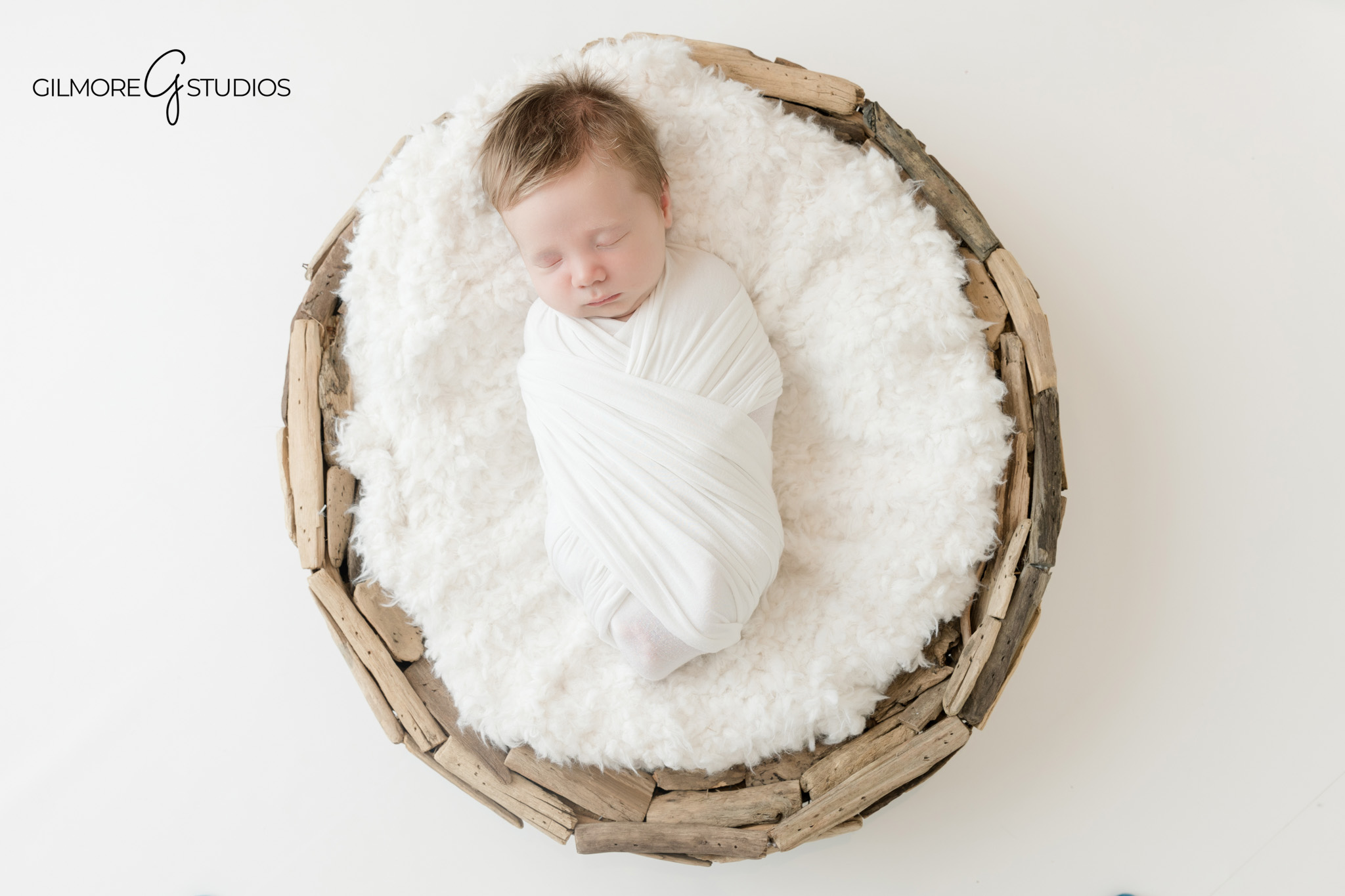 Newborn baby wrapped in white on cream studio background
Soft and simple baby boy newborn portrait at Gilmore Studios