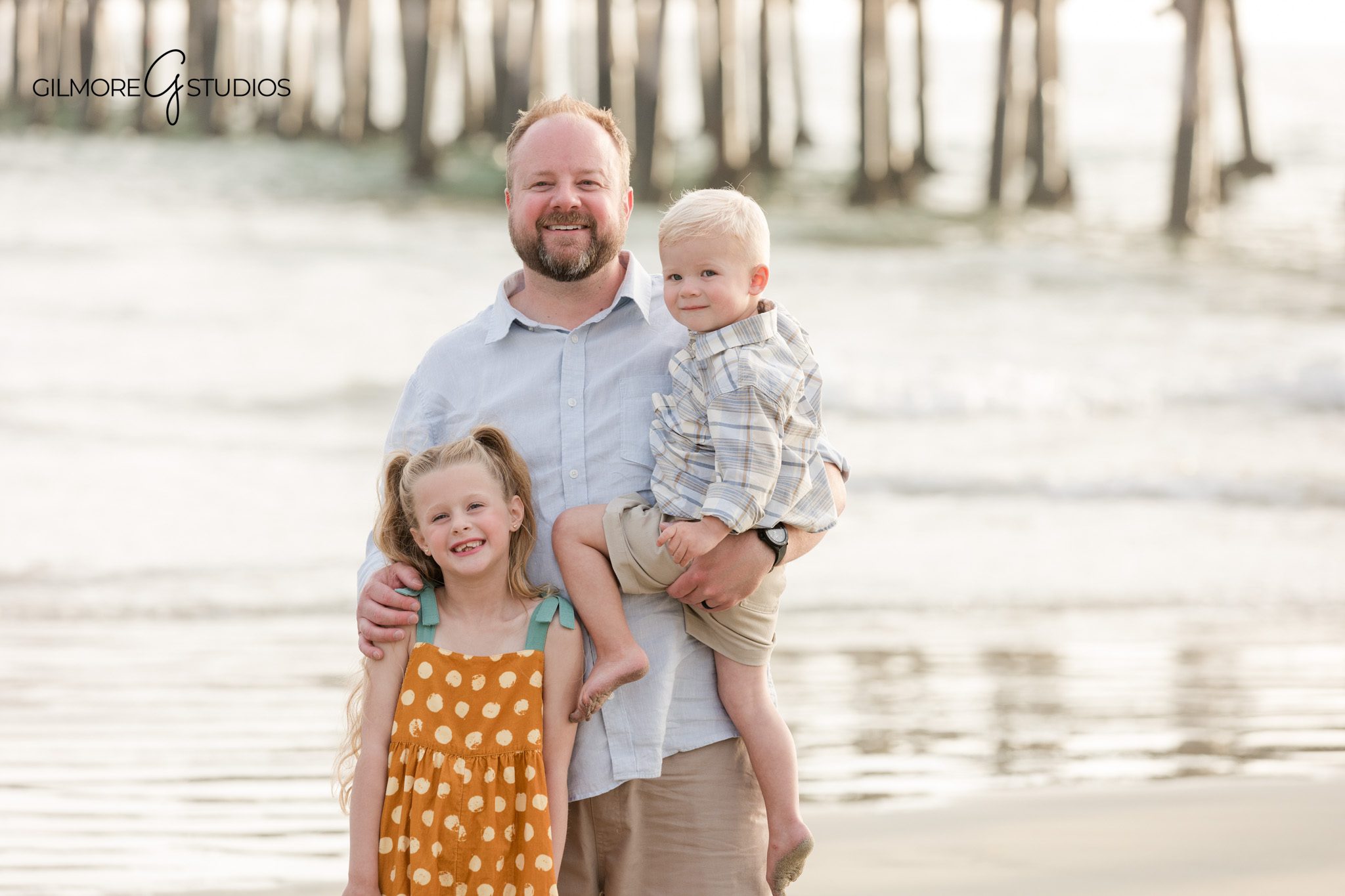 Beach family photography with soft waves and pier pilings
Coastal sibling portrait at Newport Beach Pier