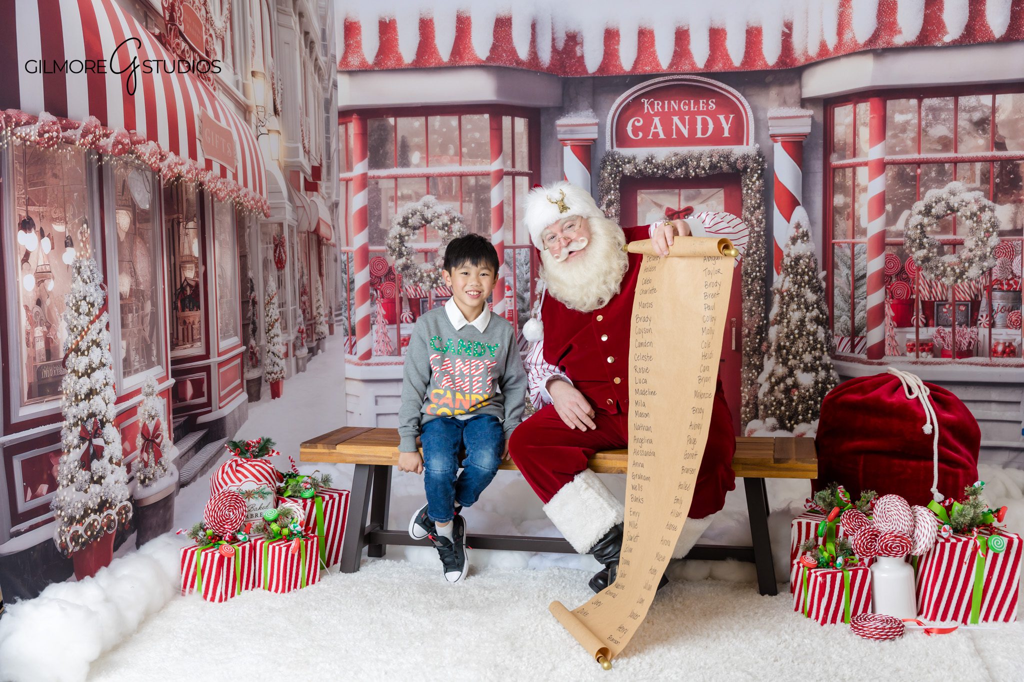 Gilbert AZ Santa session with red and white candy store backdrop
Child and Santa sitting on bench for Christmas photos