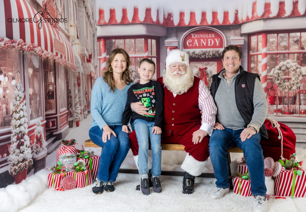 Gilmore Studios Santa mini session with candy shop backdrop
Santa reading with boys in cozy Christmas portraits