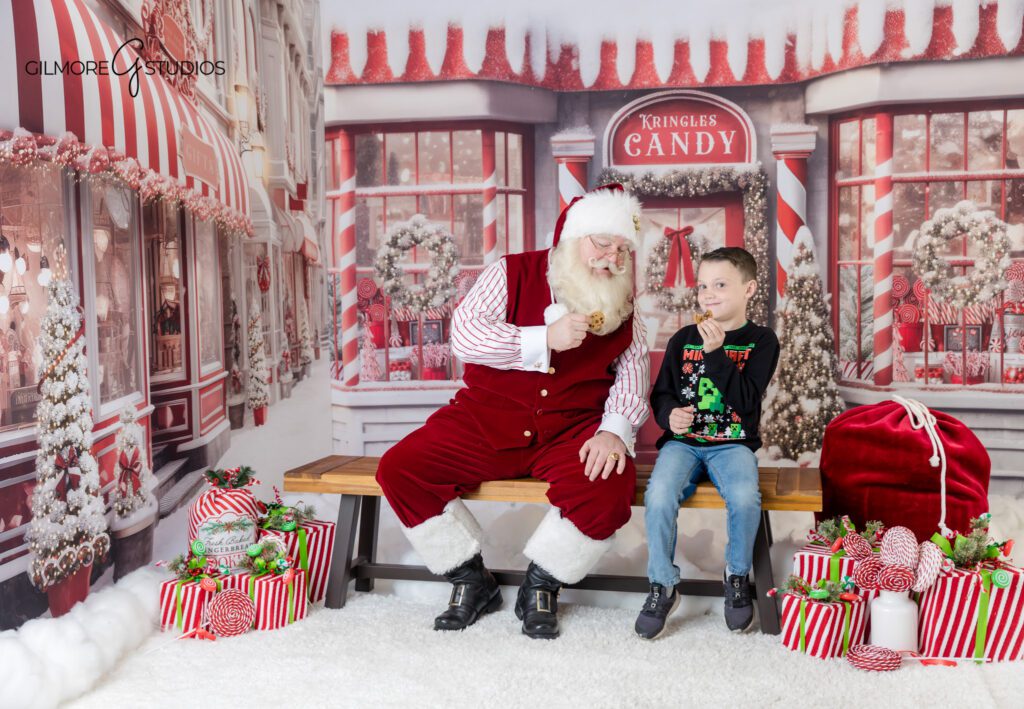 Older kids smiling with Santa during holiday mini session
Santa photos with brothers on red and white Christmas set
