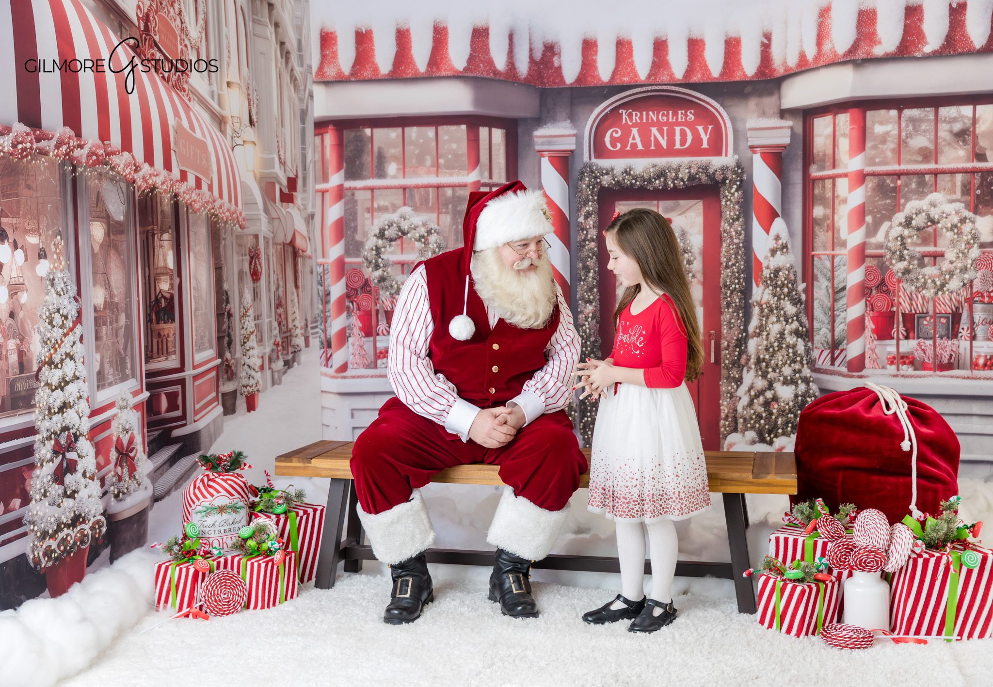 Queen Creek AZ Santa photo session with child holding Christmas cookies
Santa mini session featuring cookies, gifts, and festive red decor