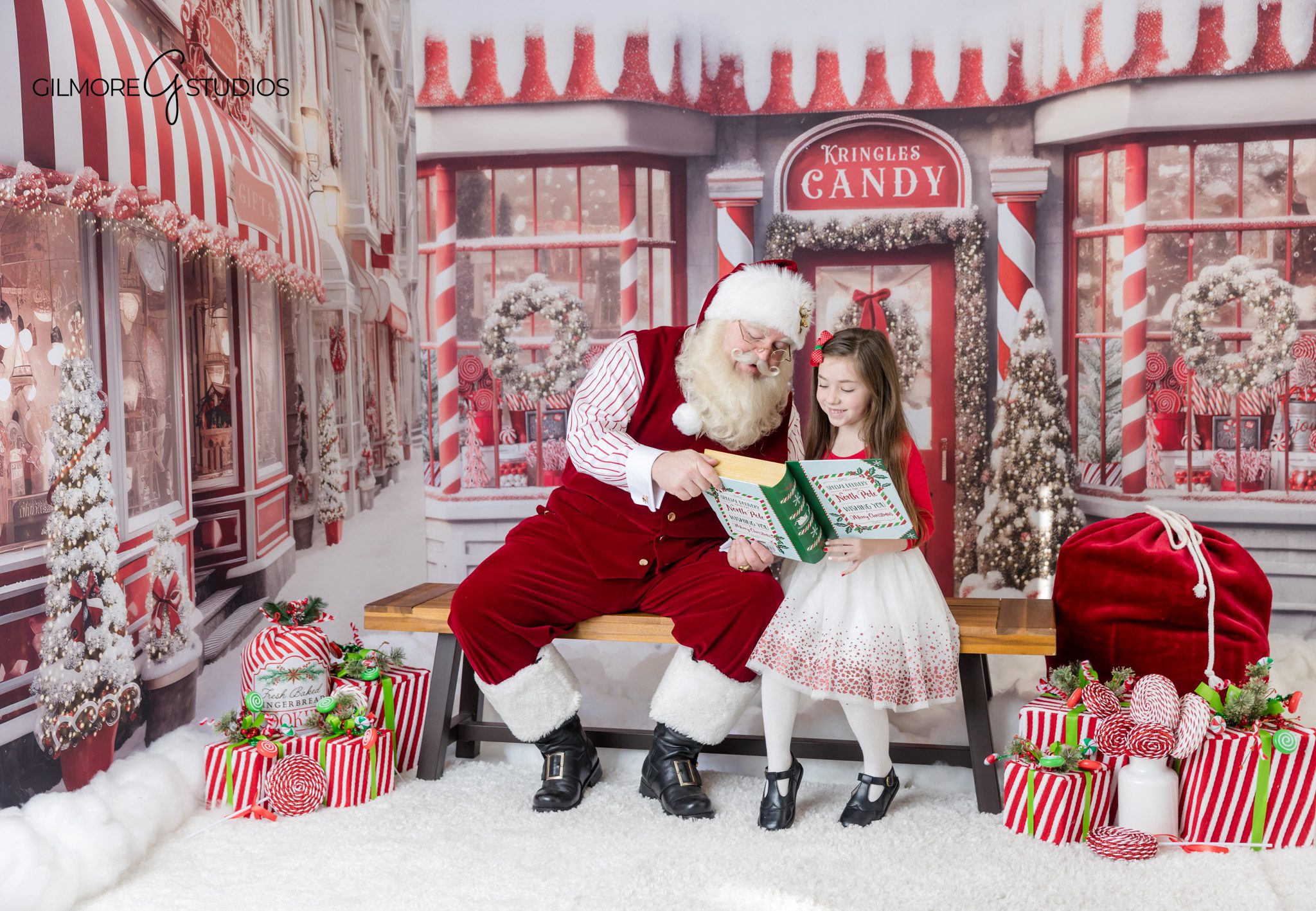 Children pointing at Santa’s nice list during a Christmas photo session
Santa mini session with red candy canes and wrapped holiday gifts