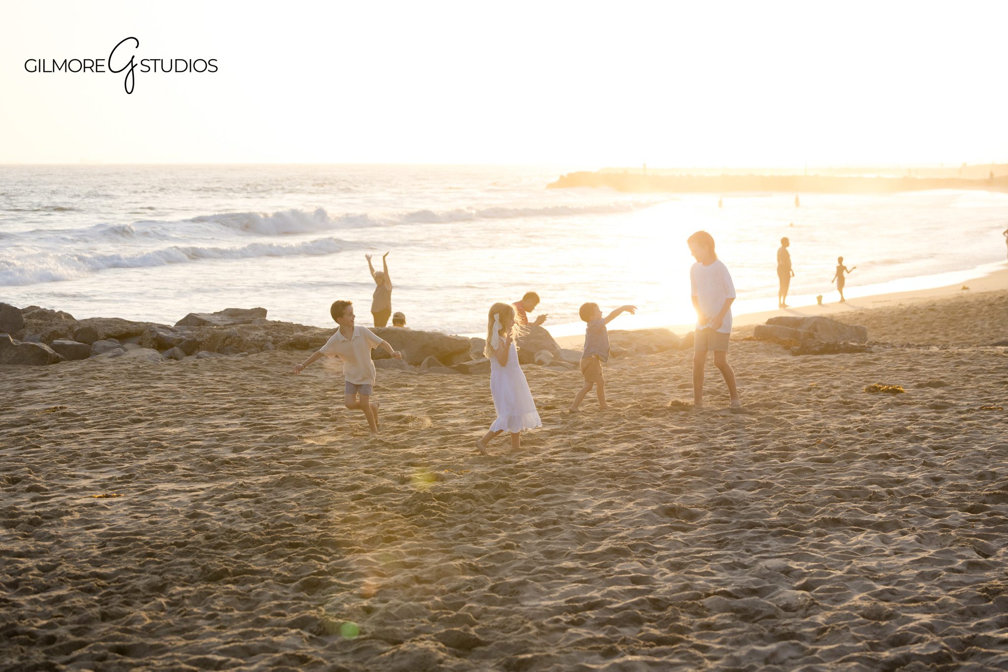 Cousins photographed together at Newport Beach during sunset
Group of children smiling on Newport Beach sand during family session