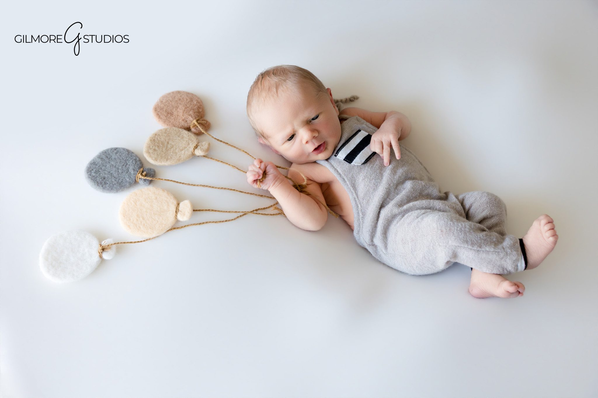 At-home newborn photography with simple baby props
Neutral newborn session with felt balloons and white blanket