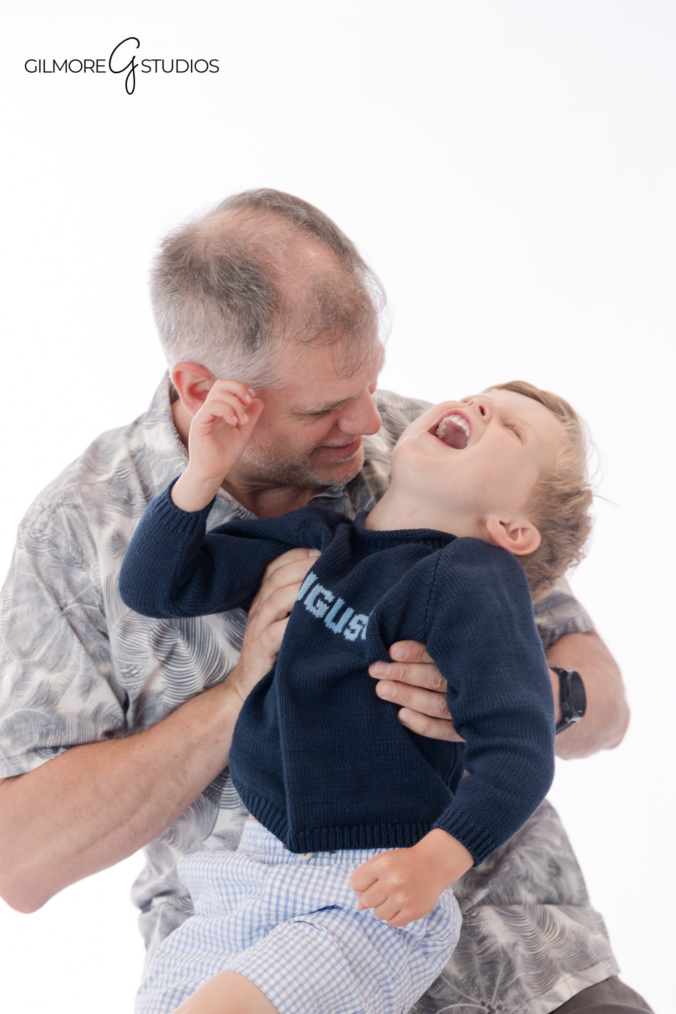 Little boy laughing during white background personality portraits
Child portrait with playful expression and navy sweater