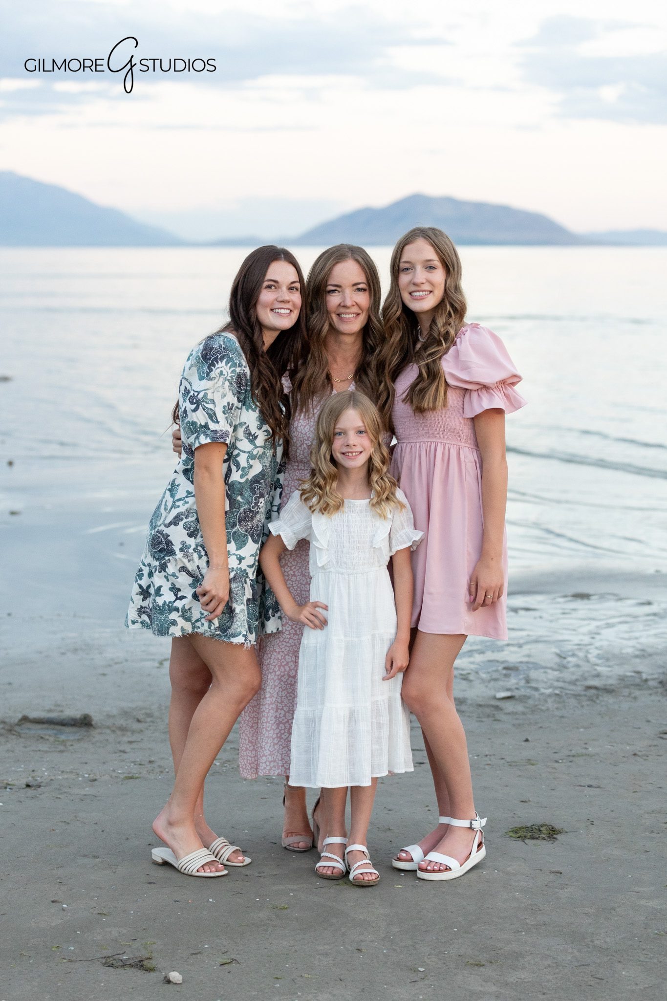 Utah family session with parents, kids, adult children, and mountains
Family portrait on the beach with calm water and cloudy skies