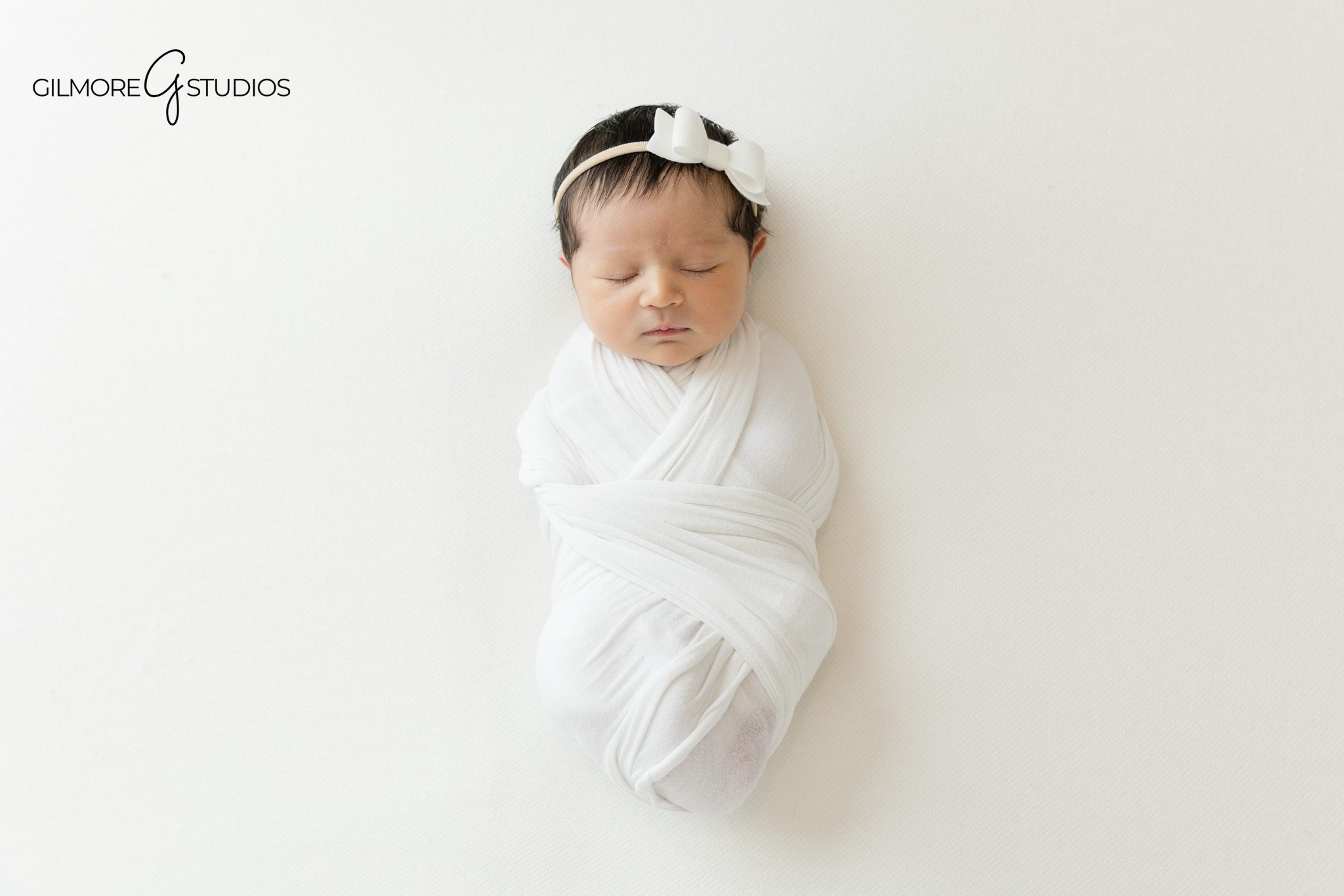Close up newborn portrait with white knit bonnet
Baby girl sleeping peacefully in white studio setup