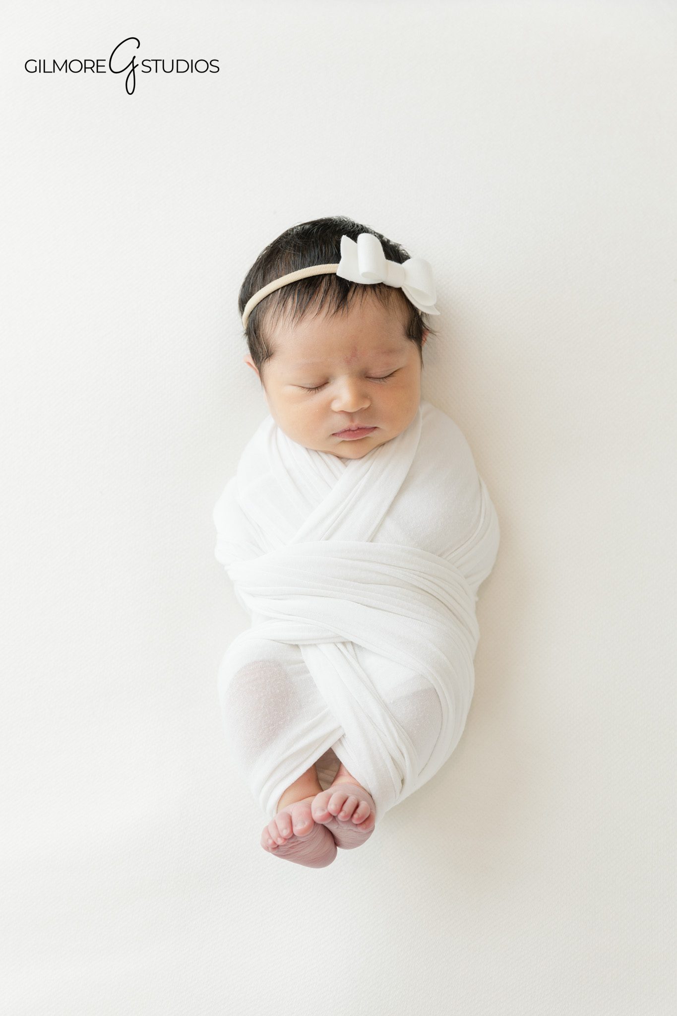 Baby girl sleeping in basket with white blanket
Overhead newborn portrait in round basket