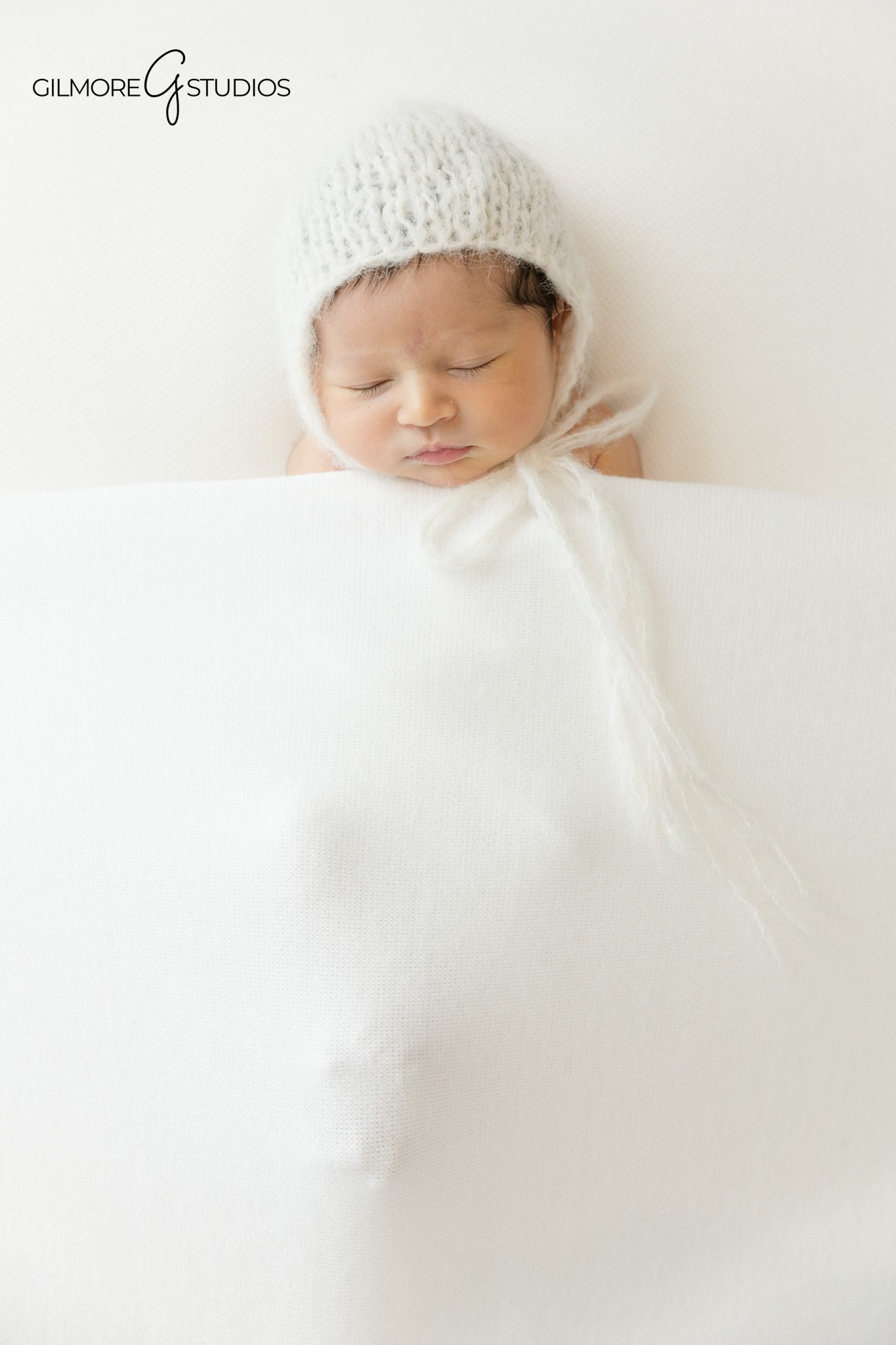 Baby girl wrapped in white during studio newborn session
Newborn family portrait with light neutral styling
