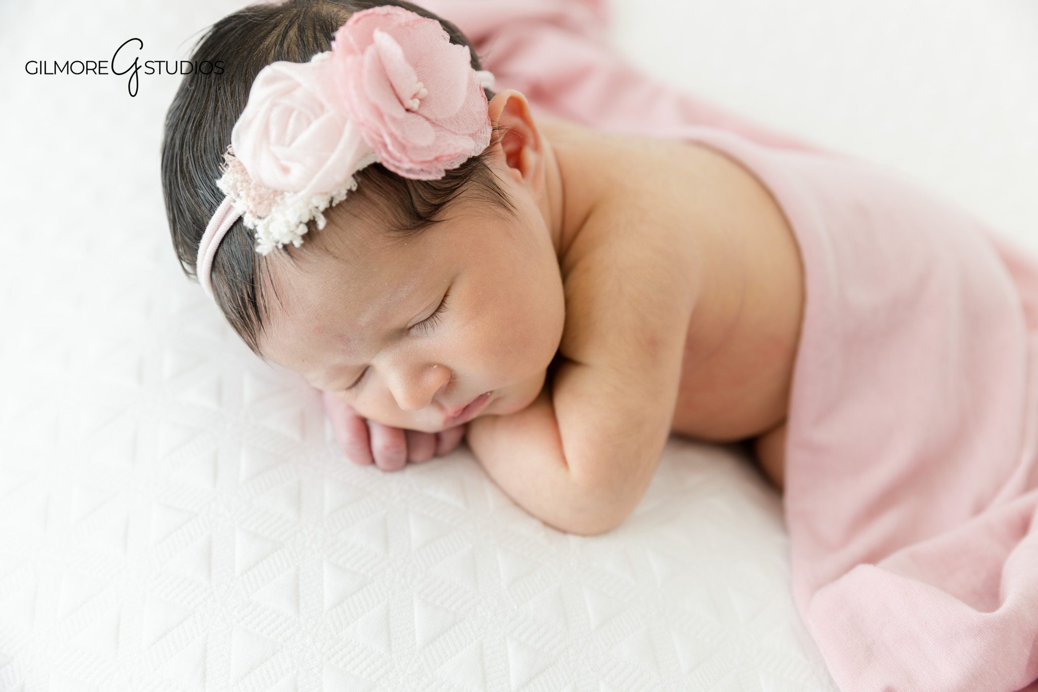 Simple studio newborn photos with white and blush styling
Baby girl newborn portrait with pink flower headband