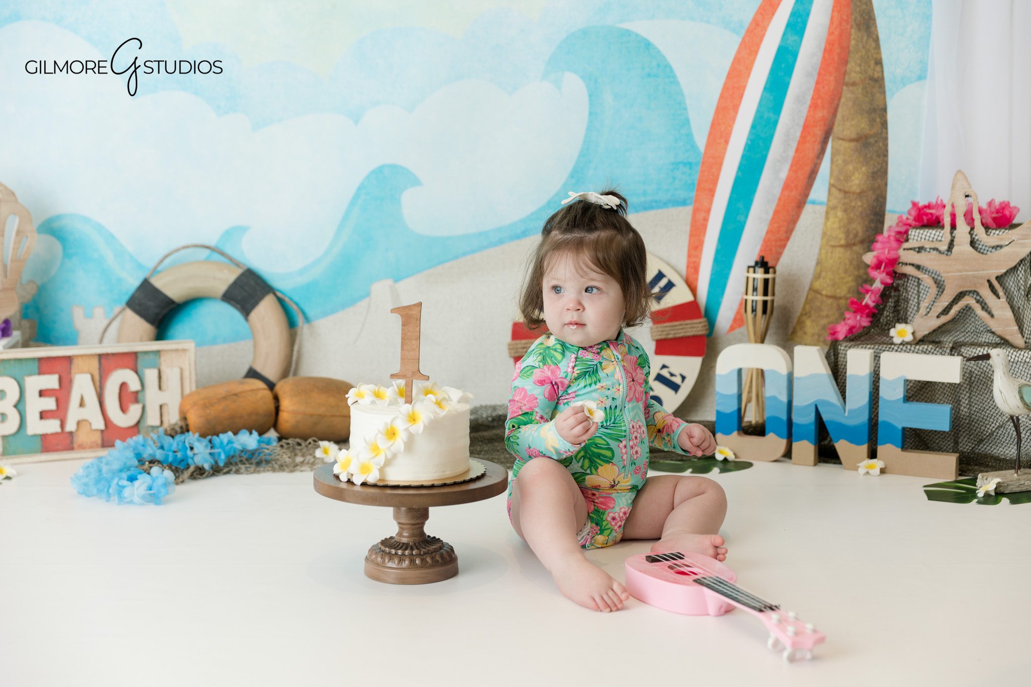 Baby girl in denim dress during outdoor milestone portraits
Outdoor baby milestone portrait in garden setting before cake smash