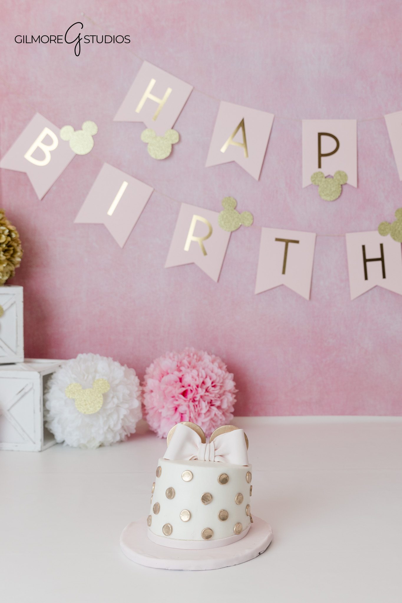 Baby girl in princess style pink dress for first birthday photos
Minnie Mouse birthday setup with pink, white, and gold decorations