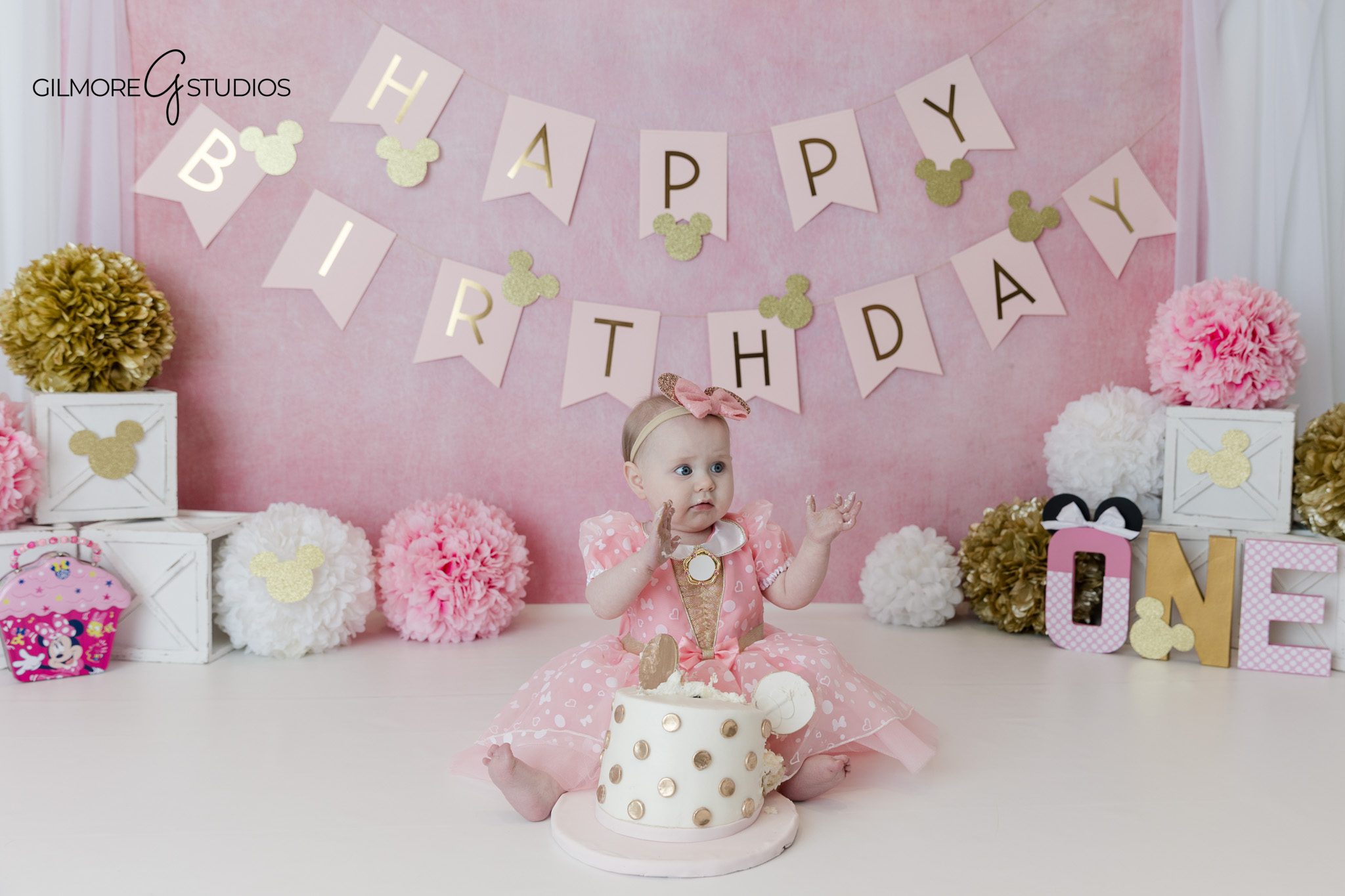 Pink and gold first birthday session with Minnie Mouse inspired details
Baby girl wearing pink bow headband for cake smash photos