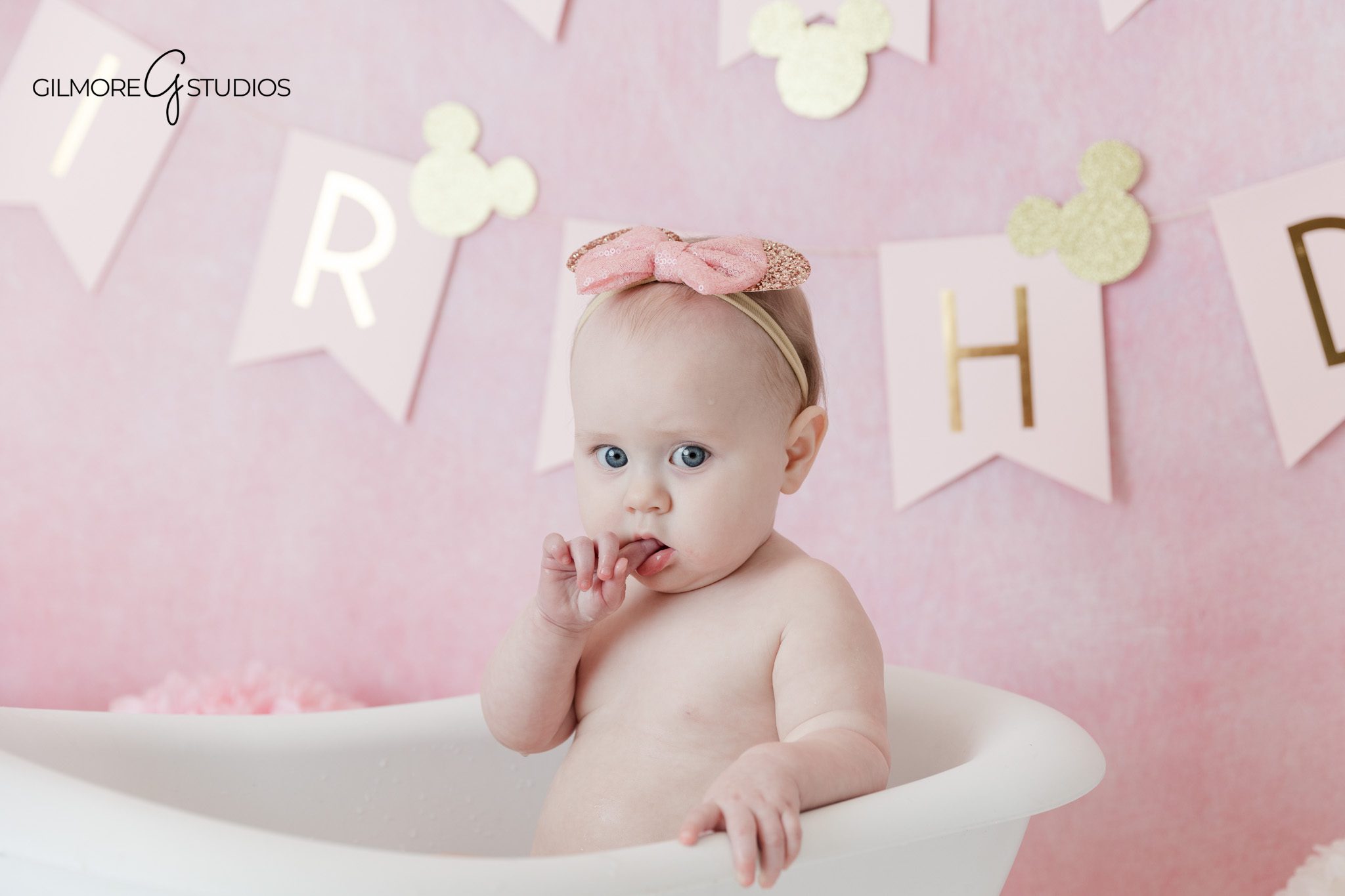 Baby girl exploring her first birthday cake in studio
Cake smash photography with pink dress and gold cake details