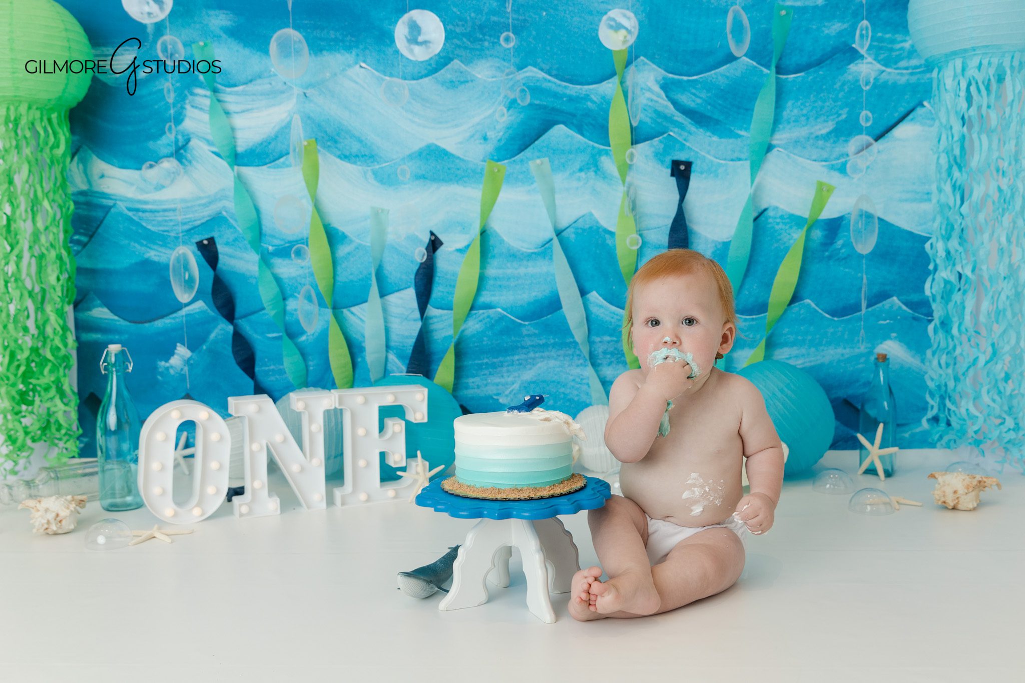 Under the sea cake smash setup with blue ocean backdrop and one year old baby
Queen Creek cake smash photographer with ocean themed birthday setup