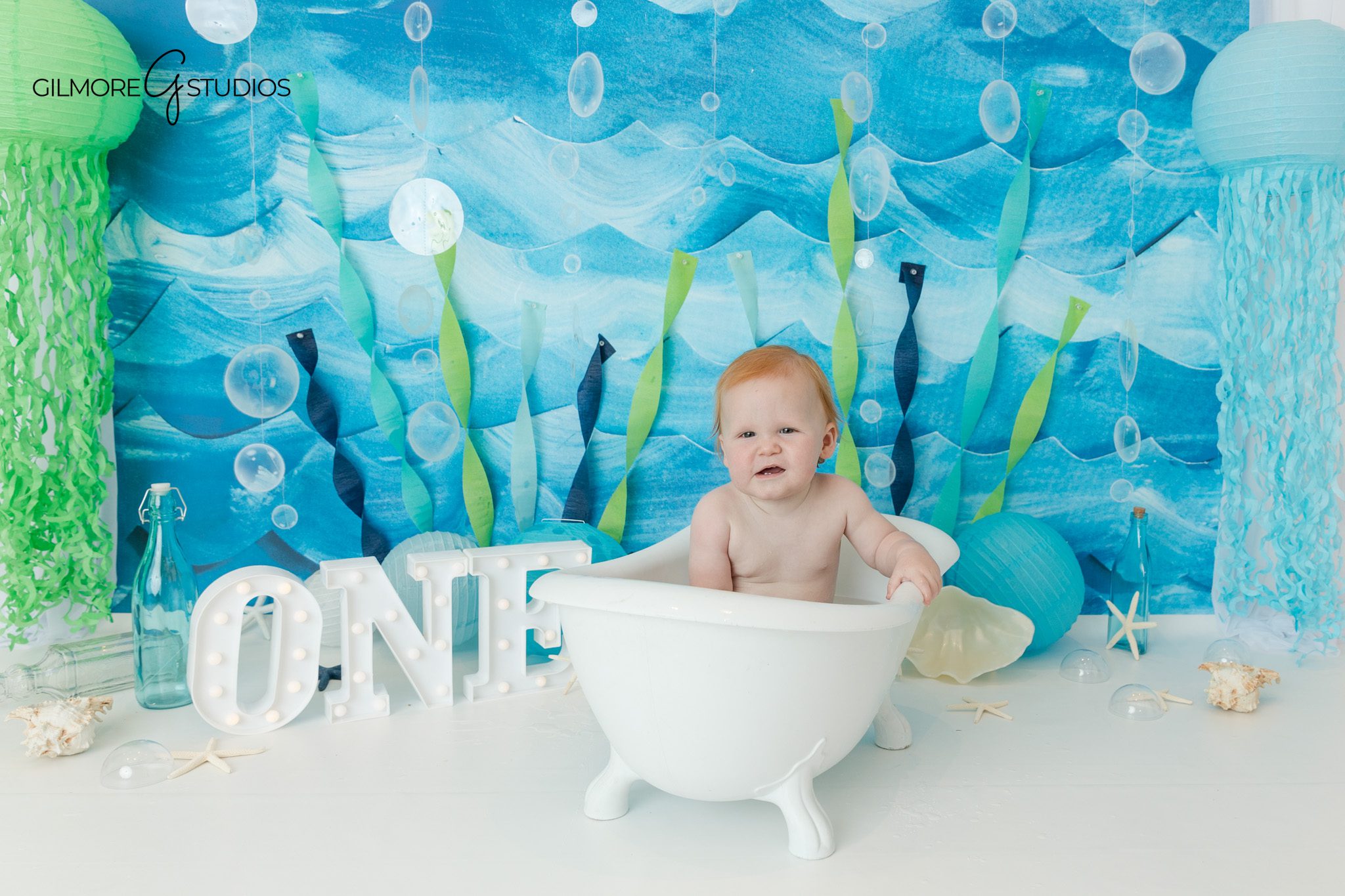 Ocean themed first birthday cake smash with starfish and seashell details
Baby boy covered in frosting during under the sea cake smash