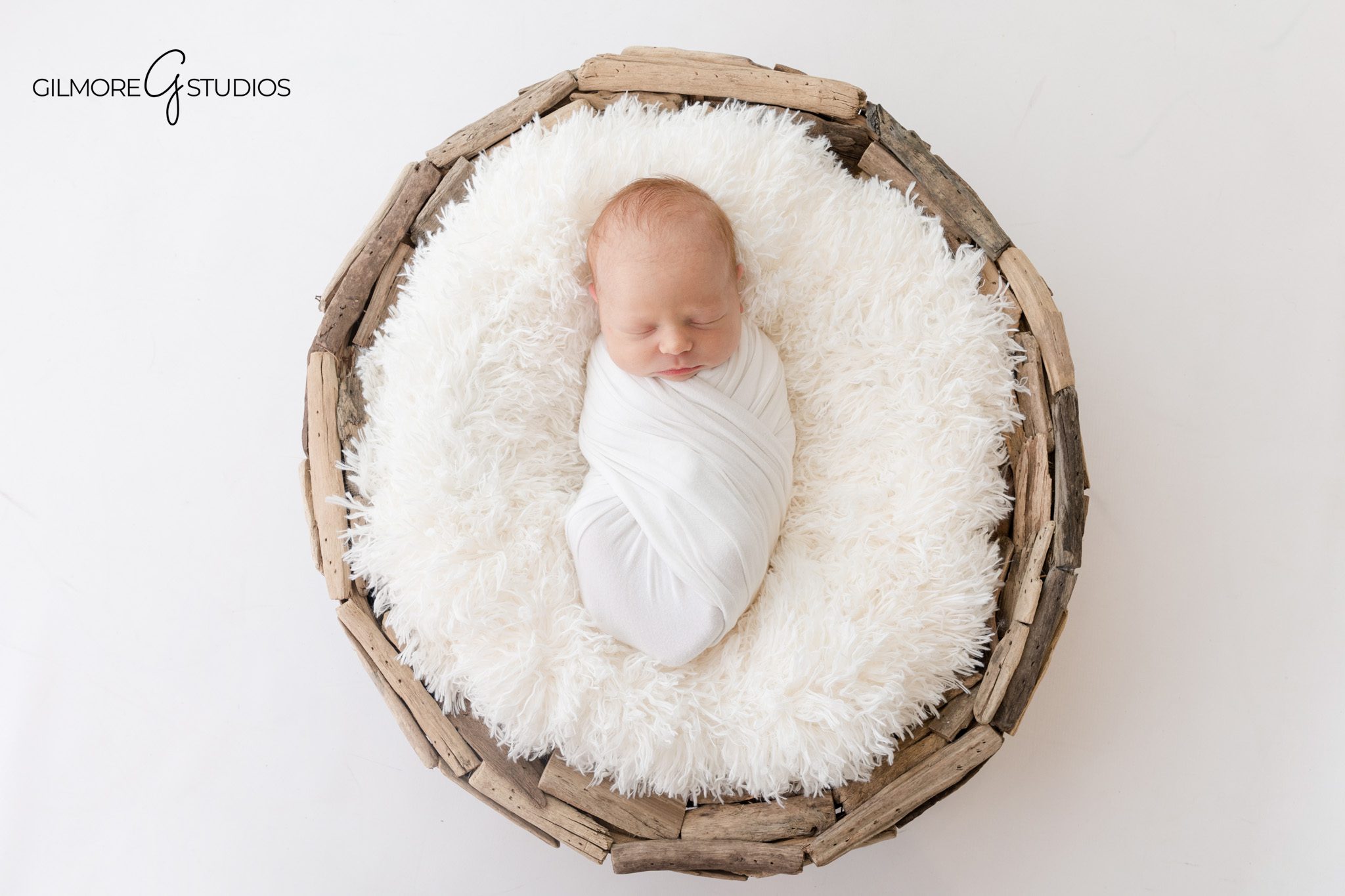 Simple newborn photography with white wrap and neutral styling
Newborn baby posed on tummy with white bonnet