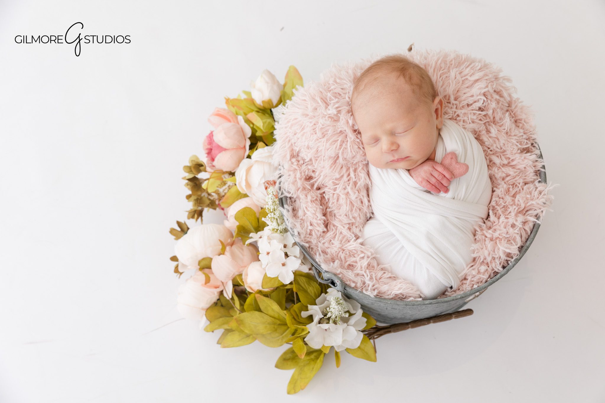 Queen Creek newborn photography with soft pink and white styling
Baby girl sleeping in white wrap with bow headband