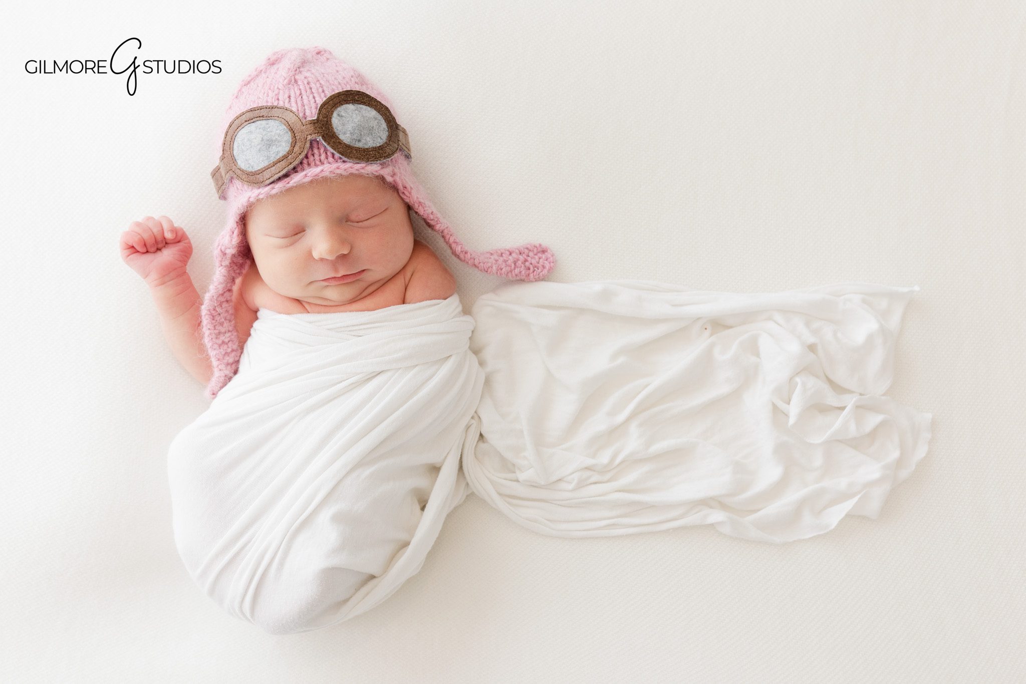 Baby girl posed in white wrap with soft natural light
Vintage airplane themed newborn photos with toy plane props