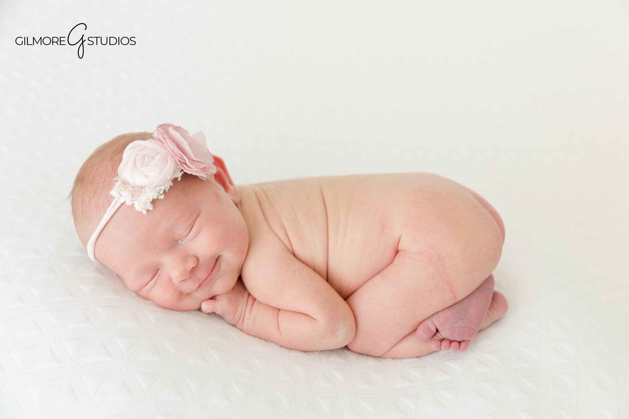 Baby girl newborn portrait with parents in a bright white studio
Newborn baby wrapped in white during Queen Creek studio session