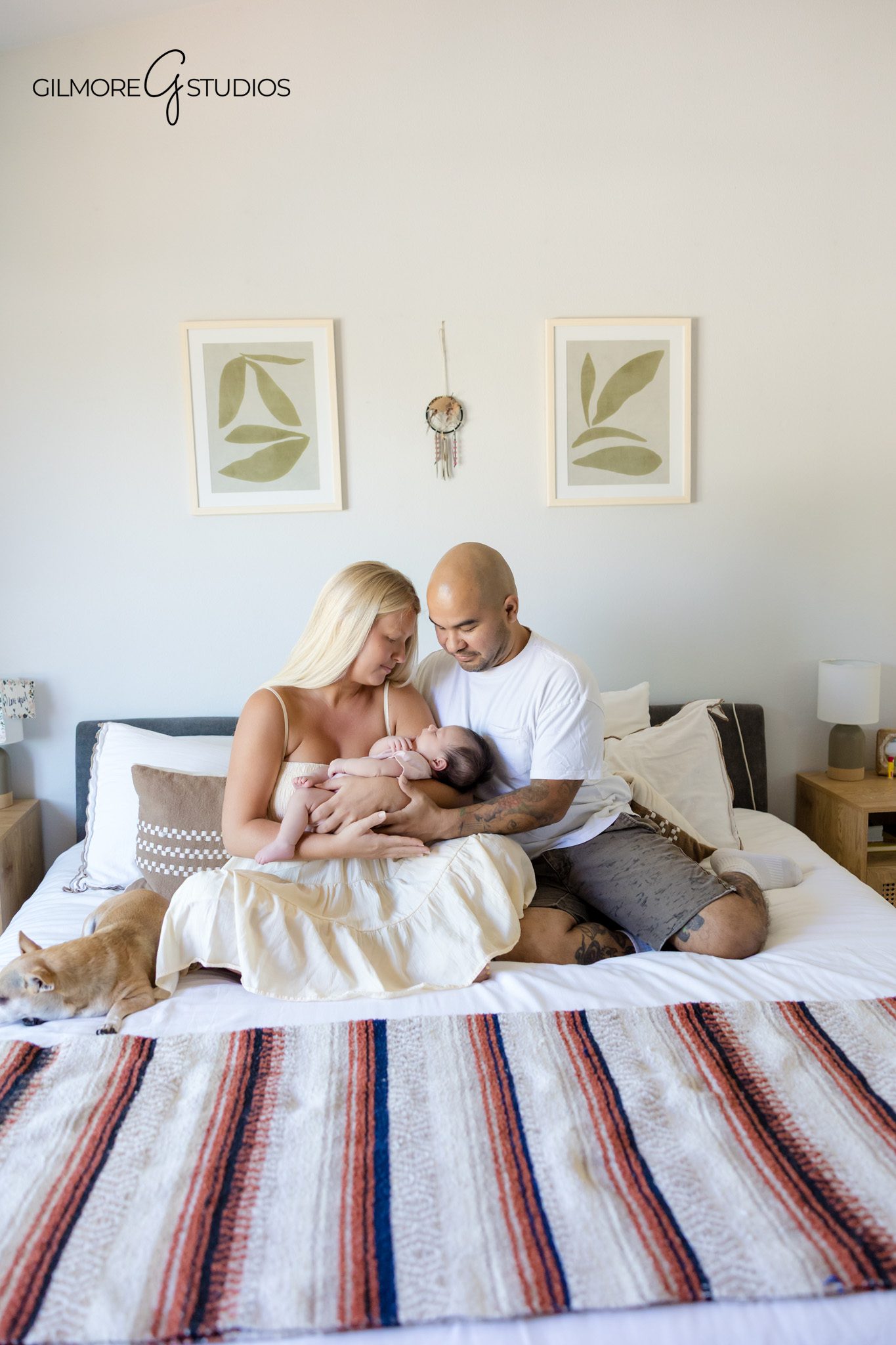 At home newborn photography with soft bedding and natural light
Parents kissing while holding newborn baby during home session